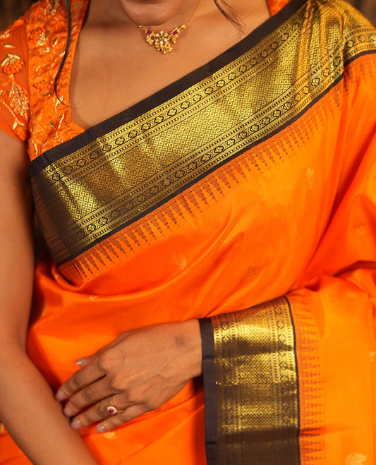 Orange Vasundhara Silk Saree, Artfully Woven with Mayil Buttas All Over Its Body, Complemented by Contrast Border Featuring Thazampoo Rekku, Muthu, Lavangam, and Mayil Kann Designs, a Grand Pallu of Jaal Designs, and Paired with a Contrast Blouse