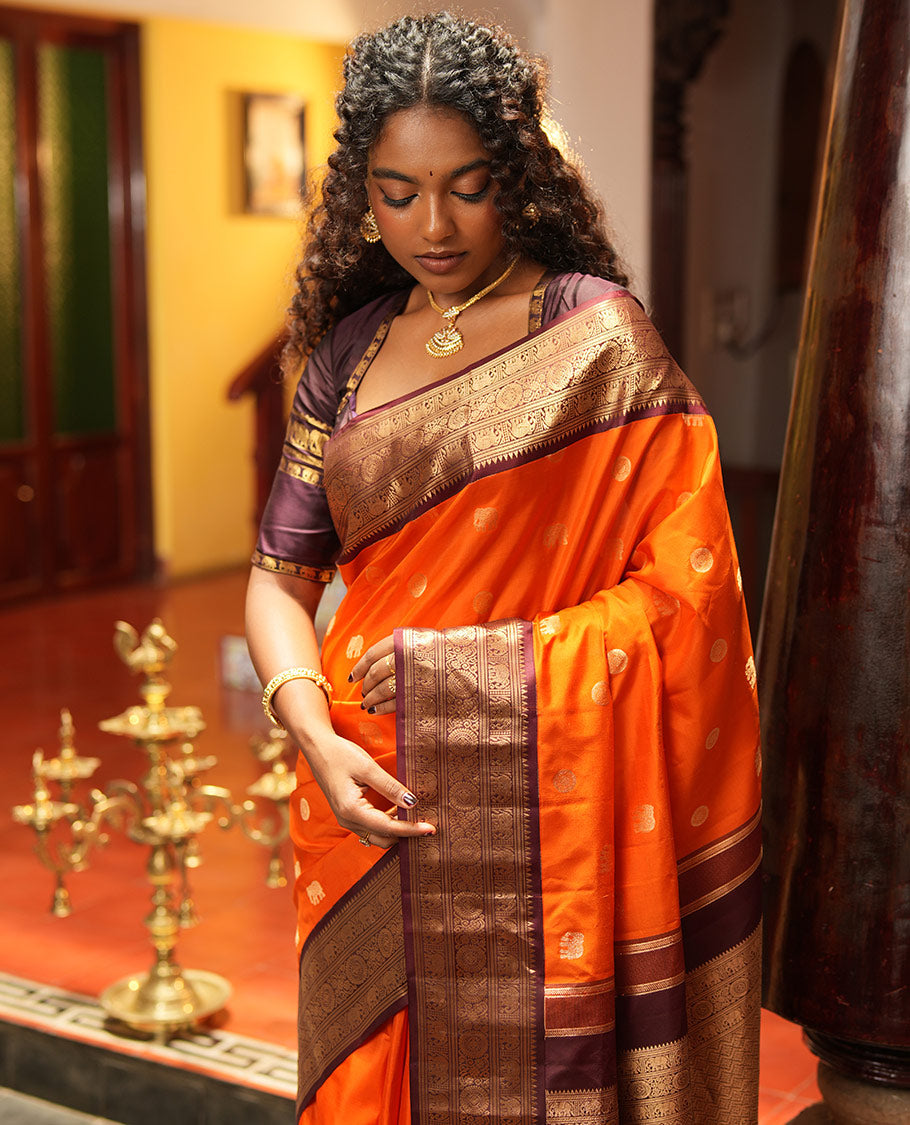 Rust Orange Vasundhara Silk Saree, Embellished with Mayil and Yaanai Buttas Across Its Body, Complemented by a Contrast Korvai Border of Rekku, Banaras, Yaanai, and Chakram Designs, Gleaming Jaal Pallu, and Paired with a Contrast Blouse