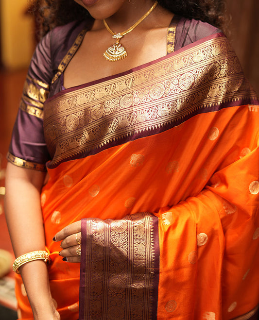 Rust Orange Vasundhara Silk Saree, Embellished with Mayil and Yaanai Buttas Across Its Body, Complemented by a Contrast Korvai Border of Rekku, Banaras, Yaanai, and Chakram Designs, Gleaming Jaal Pallu, and Paired with a Contrast Blouse