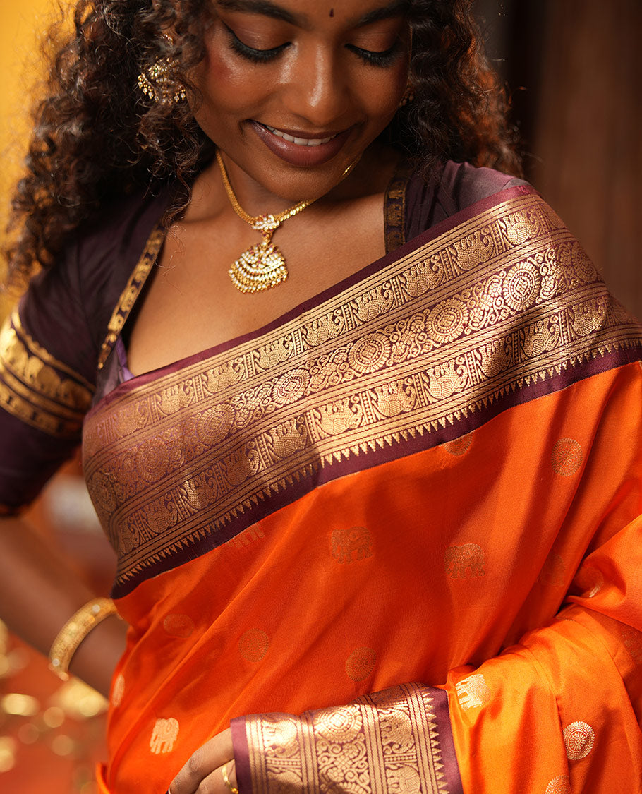 Rust Orange Vasundhara Silk Saree, Embellished with Mayil and Yaanai Buttas Across Its Body, Complemented by a Contrast Korvai Border of Rekku, Banaras, Yaanai, and Chakram Designs, Gleaming Jaal Pallu, and Paired with a Contrast Blouse