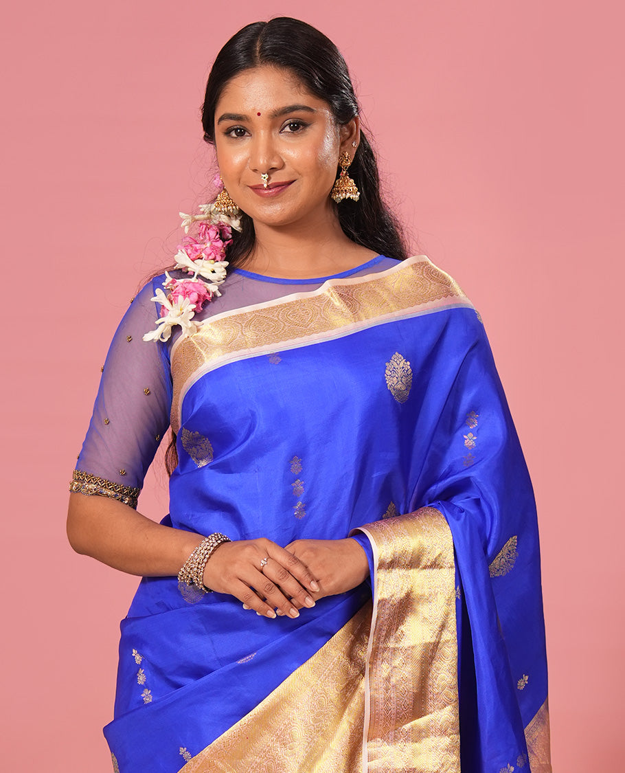 Royal blue floral zari buttas silk saree, contrast border of jada nagam, diamond, kodi visiry, and mayil designs, and zari-rich jaal pallu
