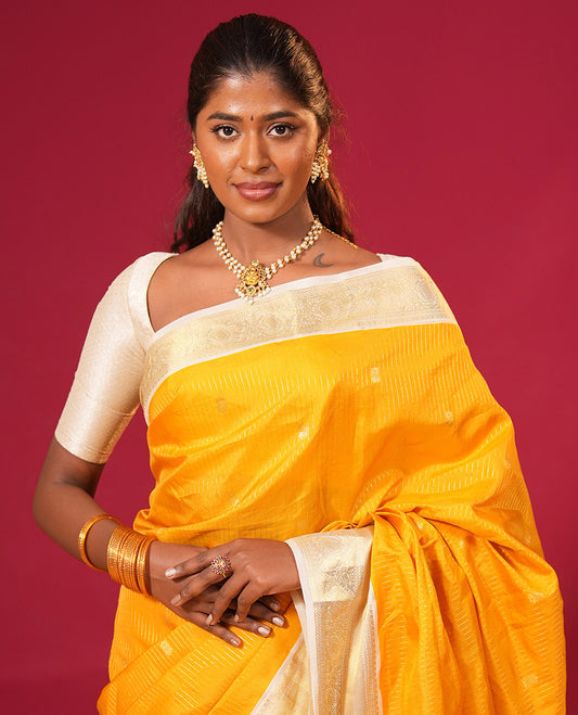 Yellow zari striped and buttas silk saree, contrast border of neli, and mayil designs in zari, and zari-rich intricate pallu