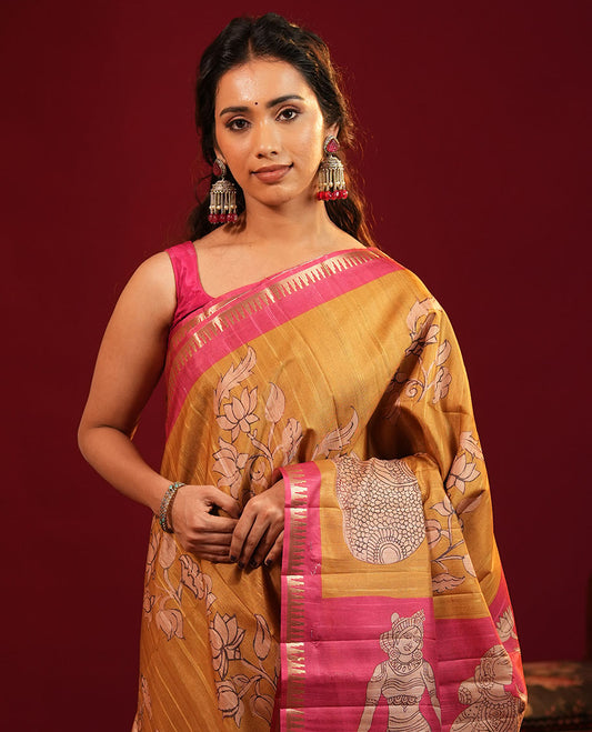Mustard Semi-Tussar Silk Saree, Elegantly Detailed with Kalamkari-Style Human Motifs Printed on Its Body, Complemented by a Contrast Temple Zari Border, Creatively Kalamkari Printed Pallu, and Paired with a Contrast Blouse