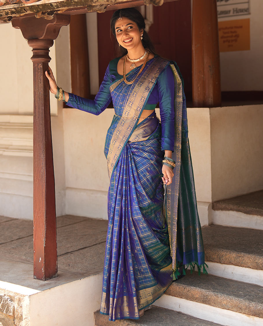 Blue Zari Buttas Enclosed in a Checked Vasundhara Silk Saree, Zari Border Adorned with Kuthirai and Chakram Designs, and Pallu Features Intricate Designs in Zari