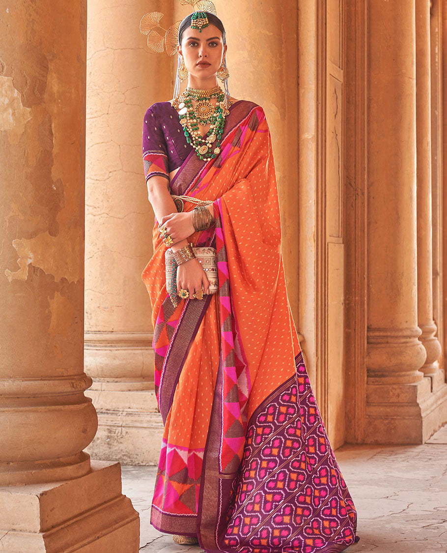Orange ikkat buttas dsigner saree, contrast geometric patterned ikkat border, and ikat-style heart motifs printed pallu