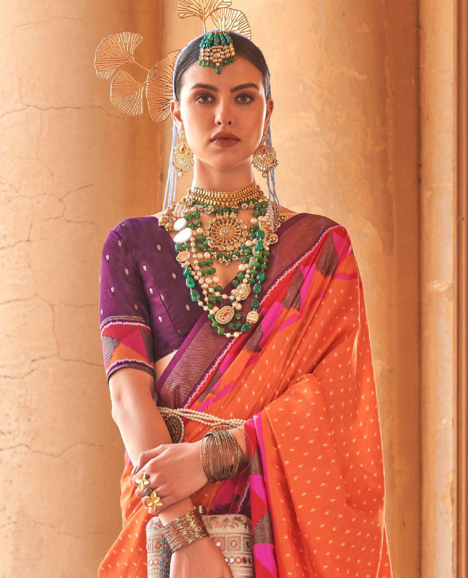 Orange ikkat buttas dsigner saree, contrast geometric patterned ikkat border, and ikat-style heart motifs printed pallu