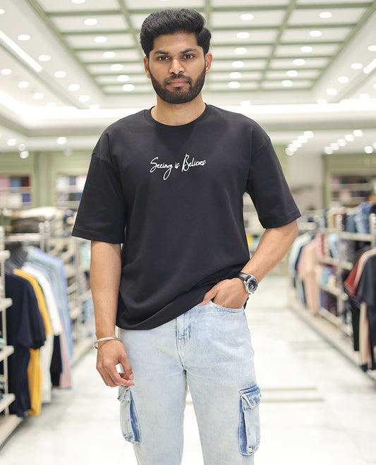 Black Glow in the Dark Cotton-Blended T-Shirt, Bedecked with Colorful Cartoon Motifs Print, Comes with a Crew Neck, Half-Sleeves, Oversized Fit, and Long Length