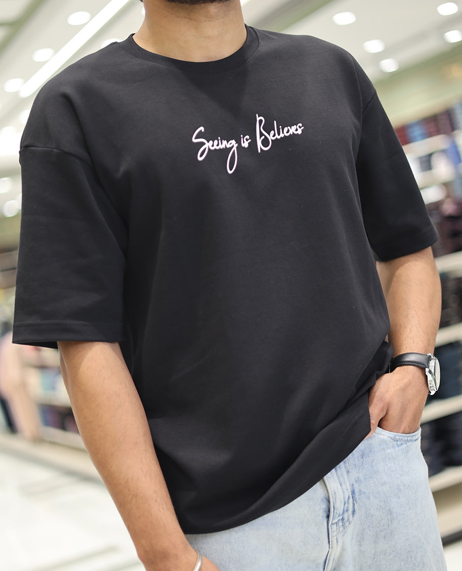 Black Glow in the Dark Cotton-Blended T-Shirt, Bedecked with Colorful Cartoon Motifs Print, Comes with a Crew Neck, Half-Sleeves, Oversized Fit, and Long Length