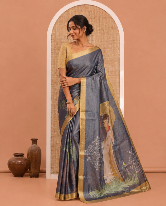 Denim Blue Kerala Culture-Themed Tissue Saree Features a Girl, Banana Leaf, and Kolam Motifs, Contrast Border, and Blouse