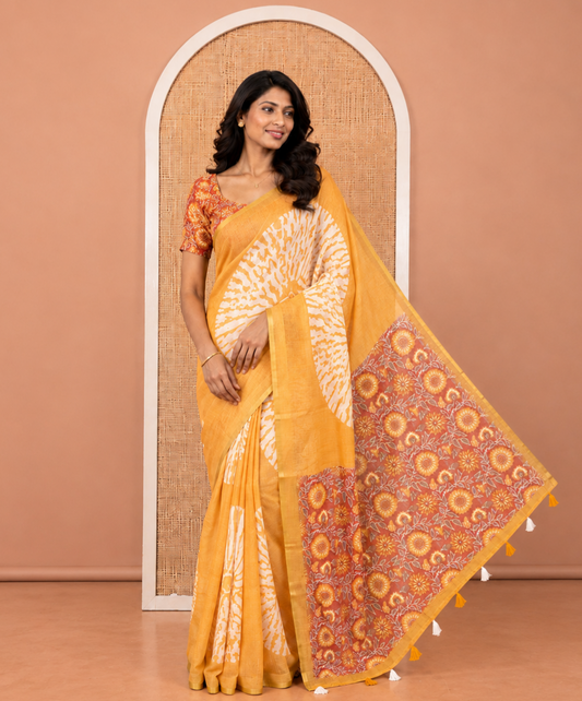 Mustard Linen Cotton Saree, Gleamed Up with Floral Motifs Printed on Its Body, Subtle Piping Border, Complemented by a Contrast Floral Printed Blouse, and Paired with a Contrast Blouse