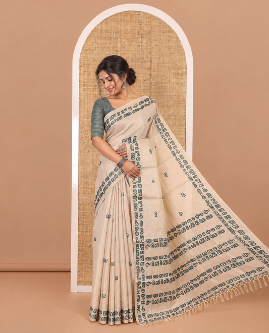 Cream-green Malayalam letter printed tissue saree, self-border and pallu steeped with Malayalam letter motifs, and a contrast plain blouse