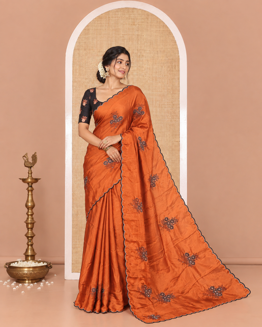 Rust Rangoli Chiffon Saree, Adorned with Flower-Style Motifs Embroidered on Its Body, a Subtle Scallop Embroidered Border, a Self-Pallu, and Paired with a Contrast Embroidered Blouse