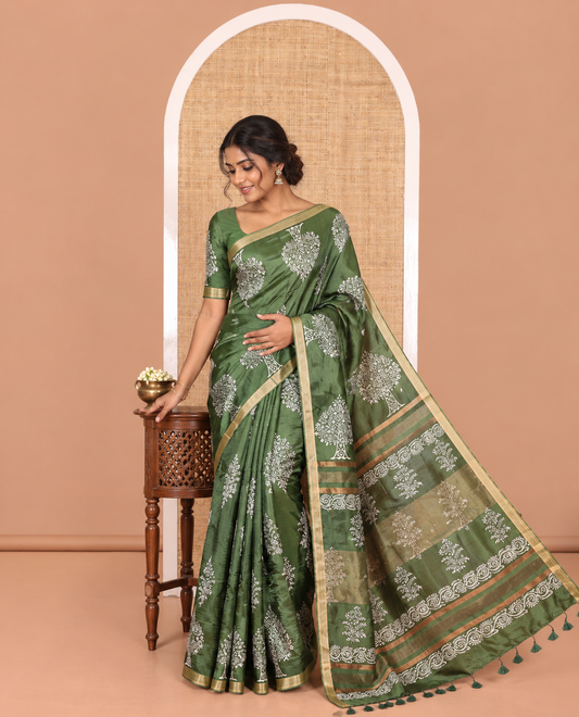 Forest green tree motifs discharge printed banana pith saree, zari piping border, floral printed pallu, and a tree discharge printed blouse