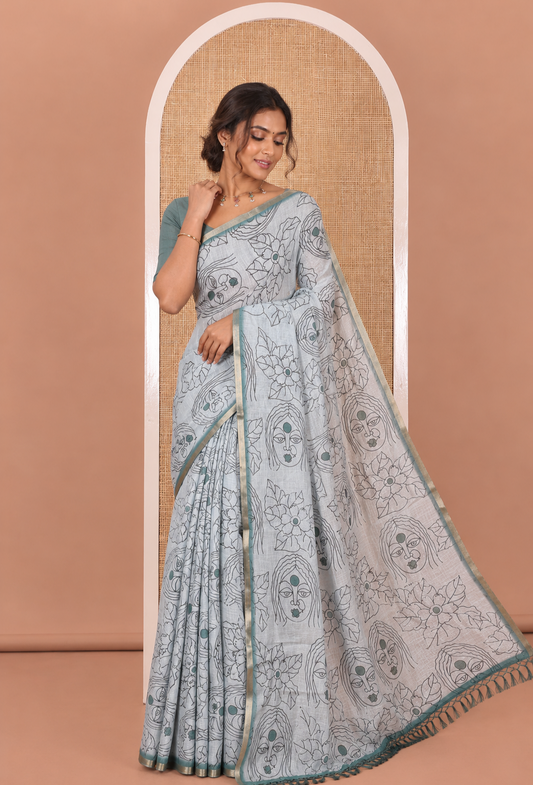 Light Green Linen Saree Creatively Printed with Girl Face and Floral Motifs All Over Its Body, Subtly Sparkled with Piping Zari Border, Pallu Mirrors the Same Body Print, and Paired with a Contrast Blouse