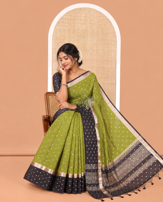Olive Green Assam Silk Saree, Charmingly Accented with Zari Buttas on Its Body, Complemented by Contrast Border Steeped with Zari Buttas, Pallu Steeped with Gleaming Zari Stripes and Buttas, and Paired with a Contrast Blouse