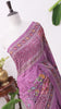 Purple saree with intricate floral patterns and mirror work draped on a mannequin, set against a simple background with plants.